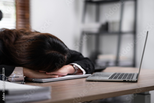 Young beautiful asian woman business worker sleeping with head on work desk at office