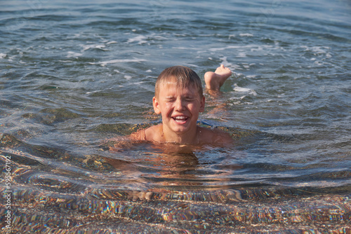 Happy joyful boy swim in sea. Portrait of cheerful child. Sunny summer day, holiday vacation