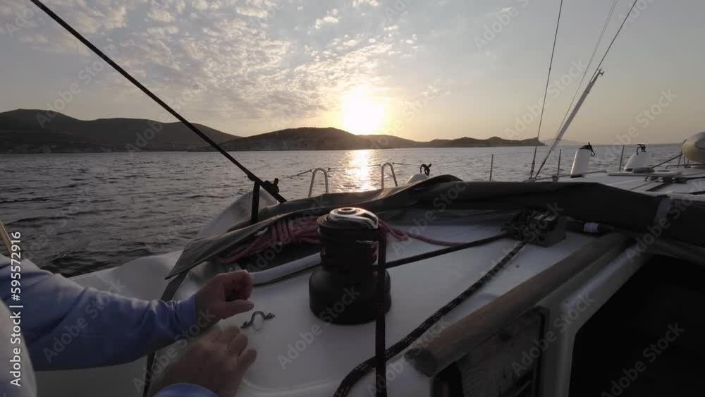 Sailor's hand on a winch of sailing boat against the sunset. Man