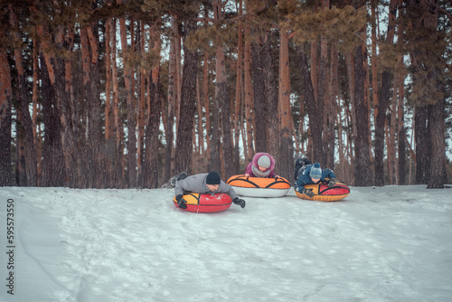Children and parents have fun riding from the snowy mountain on tubing. Group of children sliding down on tubes.