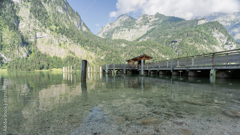 Wooden pier located on alpine lake surrounded by mountains, Konigssee, Germany Wooden pier located on alpine lake surrounded by mountains, Konigssee, Germany