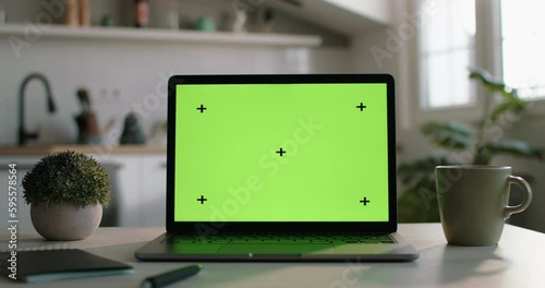 Template for inserting videos, chromakey on laptop. Modern laptop with mock up chroma key green screen on table of living room, desk set up for work at home. Technology concept close up template. 