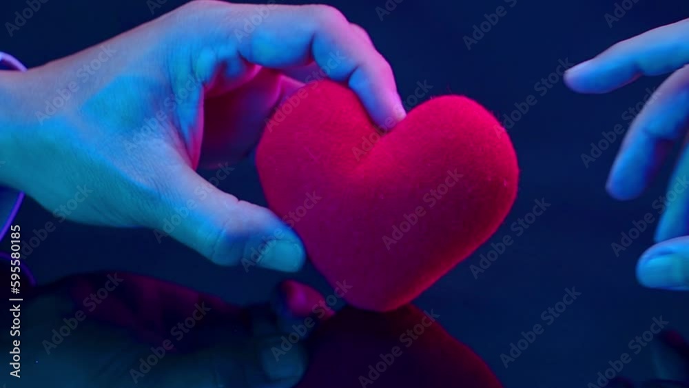Hand holding and giving red heart to receiving hand. Concept of love, valentine's day, giving, hope, support, friendship, family, charity, donate, health care, insurance, peace, and helping hand.