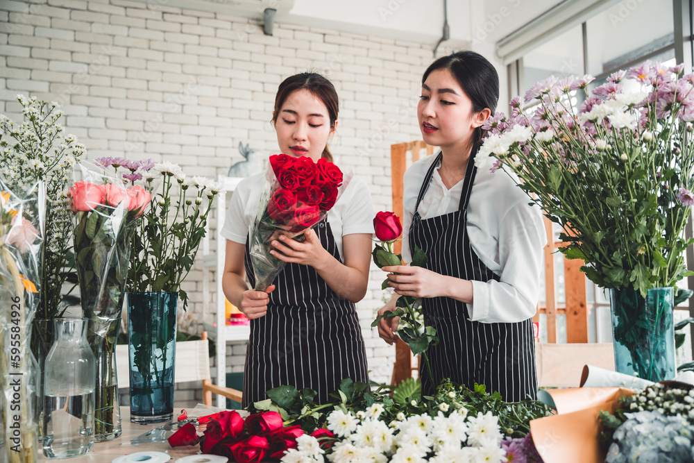 Two female employees meticulously arrange flowers for customers in a flower shop.