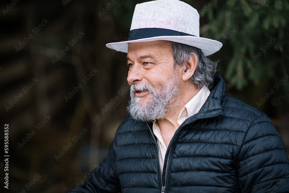 Portrait of a smiling, confident, handsome, mature man during his walk in the forest