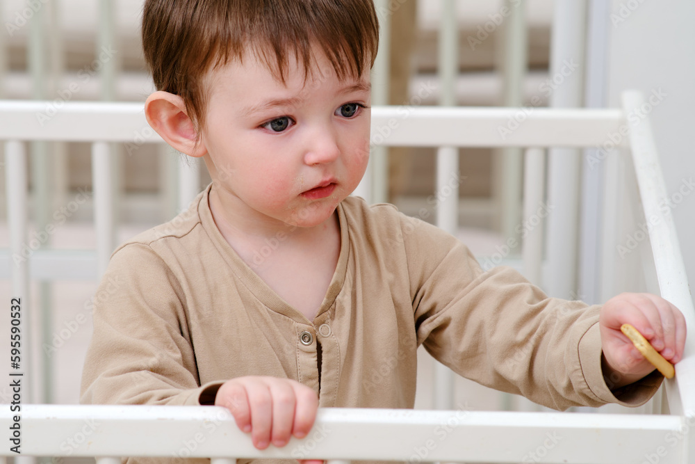 Child eats cookies in a crib. Feeding a baby in bed like in a playpen. Kid aged about two years (one year nine months) Child eats cookies in a crib. Feeding a baby in bed like in a playpen. Kid aged about two years (one year nine months)