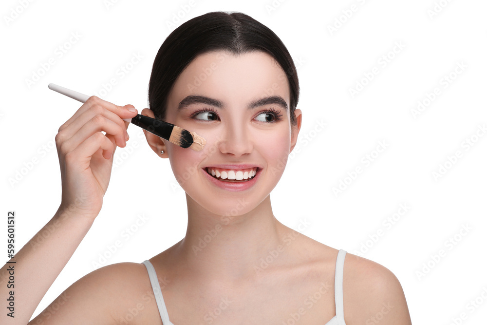 Teenage girl applying foundation on face with brush against white background Teenage girl applying foundation on face with brush against white background