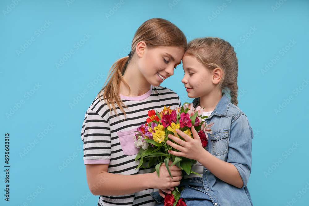Little daughter congratulating her mom with flowers on light blue background. Happy Mother's Day Little daughter congratulating her mom with flowers on light blue background. Happy Mother's Day