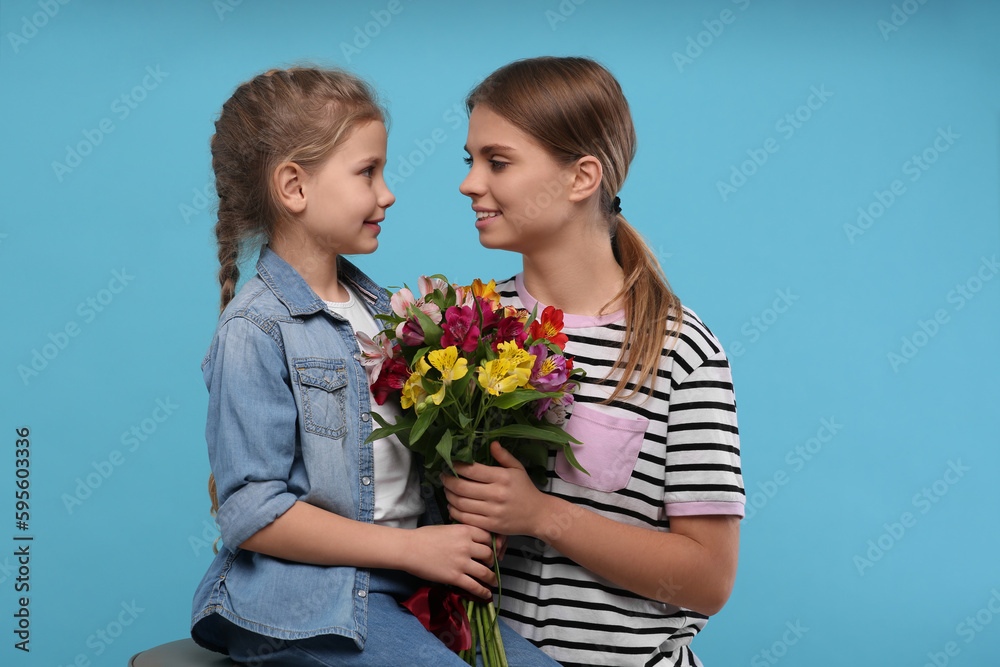 Little daughter congratulating her mom with flowers on light blue background. Happy Mother's Day Little daughter congratulating her mom with flowers on light blue background. Happy Mother's Day