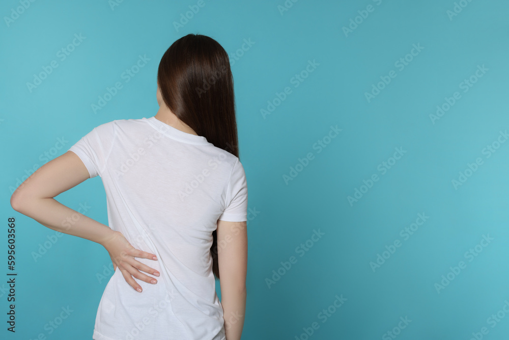 Woman suffering from back pain on light blue background, space for text. Arthritis symptoms Woman suffering from back pain on light blue background, space for text. Arthritis symptoms