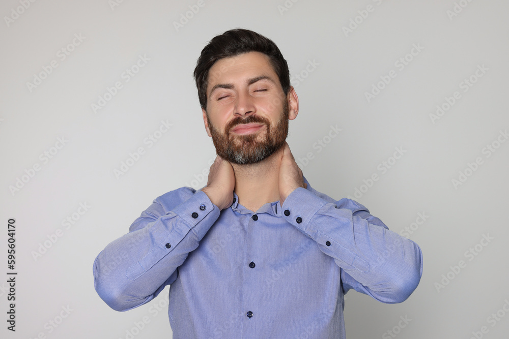 Man suffering from pain in his neck on light background. Arthritis symptoms Man suffering from pain in his neck on light background. Arthritis symptoms