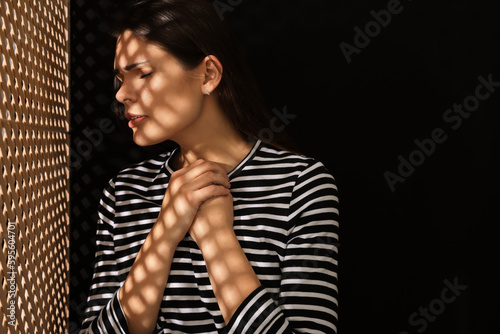 Upset woman listening to priest during confession near wooden partition in booth, space for text