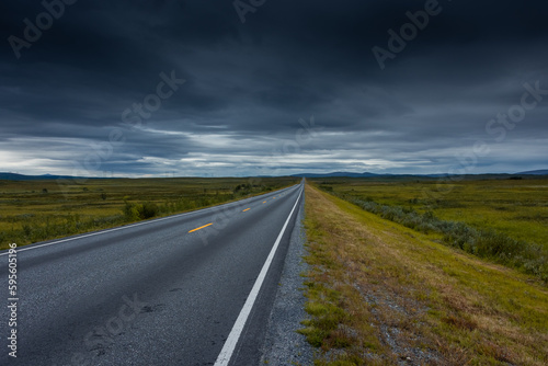 Epic cloudy landscape of an empty highway through the tundra of Norway