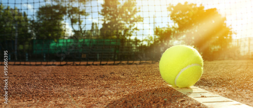 Bright yellow tennis ball on clay court, space for text. Banner design © New Africa