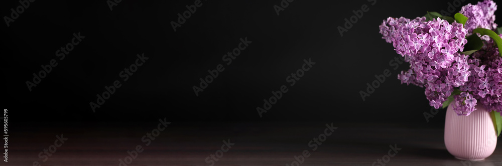 Beautiful lilac flowers in vase on wooden table against black background, space for text. Banner design