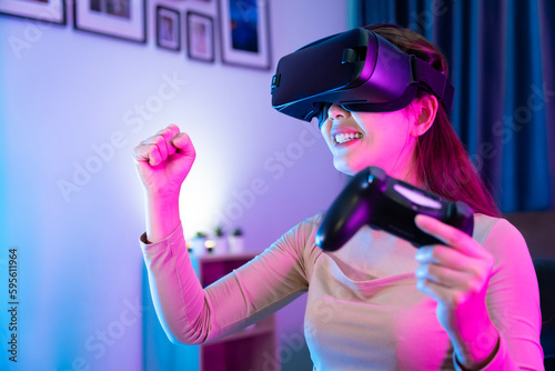 Asian modern female gamer having serious fun playing games from VR console in RGB gaming room. © SKW