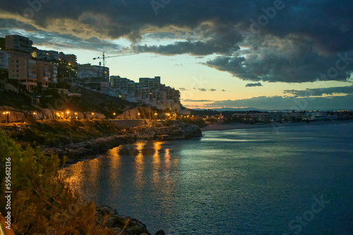 a view of the sea at dusk with buildings in the background