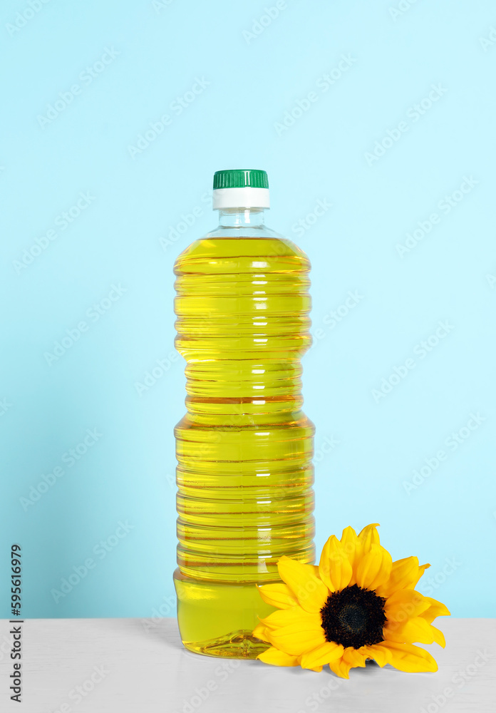 Bottle of cooking oil and sunflower on white table Bottle of cooking oil and sunflower on white table