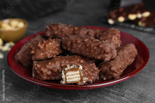 Plate of tasty chocolate bars with caramel on light grey table