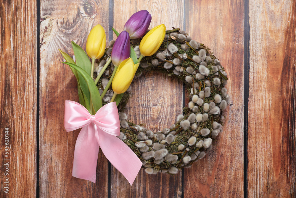 Wreath made of beautiful willow, colorful tulip flowers and pink bow on wooden background, top view Wreath made of beautiful willow, colorful tulip flowers and pink bow on wooden background, top view