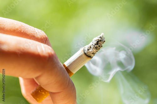 cigarette smoking consumable. Smoking addiction concept. Smoking woman with background of nature and danger by fire. Close up view and copy space of cigarette with smoke and ash