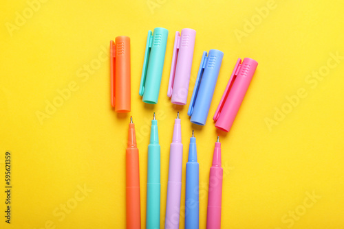 Many colorful markers on yellow background  flat lay