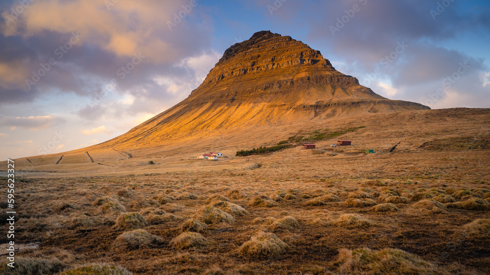 Stunning shot of Kirkjufell mountain in Iceland during a breathtaking sunset. The mountain's distinctive shape, combined with the vibrant colors of the setting sun, creates a magical moment.