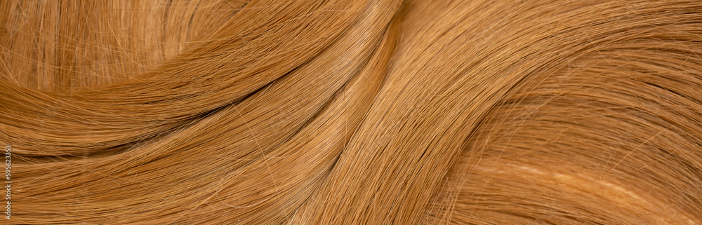 Obraz premium Red hair close-up as a background. Women's long orange hair. Beautifully styled wavy shiny curls. Hair coloring bright shades. Hairdressing procedures, extension.