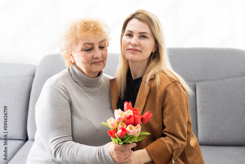 Happy mother's day. Beautiful young woman and her mother with flowers at home. Happy mother's day. Beautiful young woman and her mother with flowers at home.