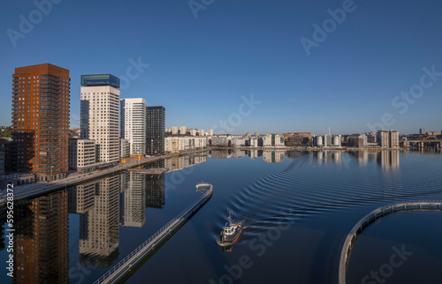 Train bridge view at the bay   rstaviken  apartment skyscrapers reflecting and a tug boat passing bridge  a tranquil early sunny spring day in Stockholm