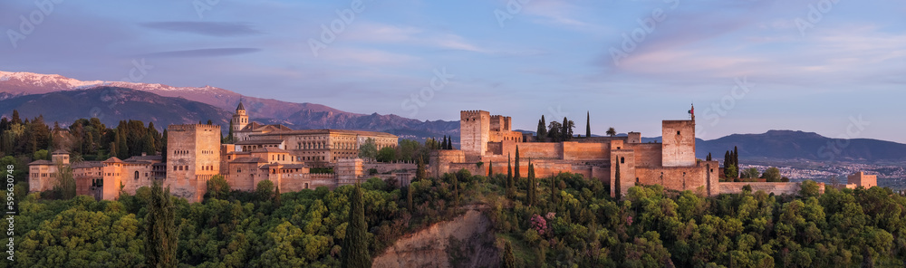 Alhambra is medieval palace and fortress complex with Sierra Nevada snowy mountains in Granada, Andalusia, Spain. Known as a Capital of Nasrid Kingdom or Emirate of Granada. Panoramic sunset hour time