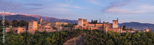 Alhambra is medieval palace and fortress complex with Sierra Nevada snowy mountains in Granada, Andalusia, Spain. Known as a Capital of Nasrid Kingdom or Emirate of Granada. Panoramic sunset hour time