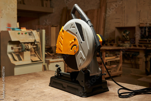 A new stylish cutting off abrasive disc machine stands on a wooden workbench in a carpentry workshop