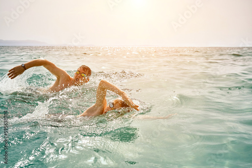 Father and son swim in the sea, family in swimming goggles at view enjoying summer vacation. Togetherness Friendly concept