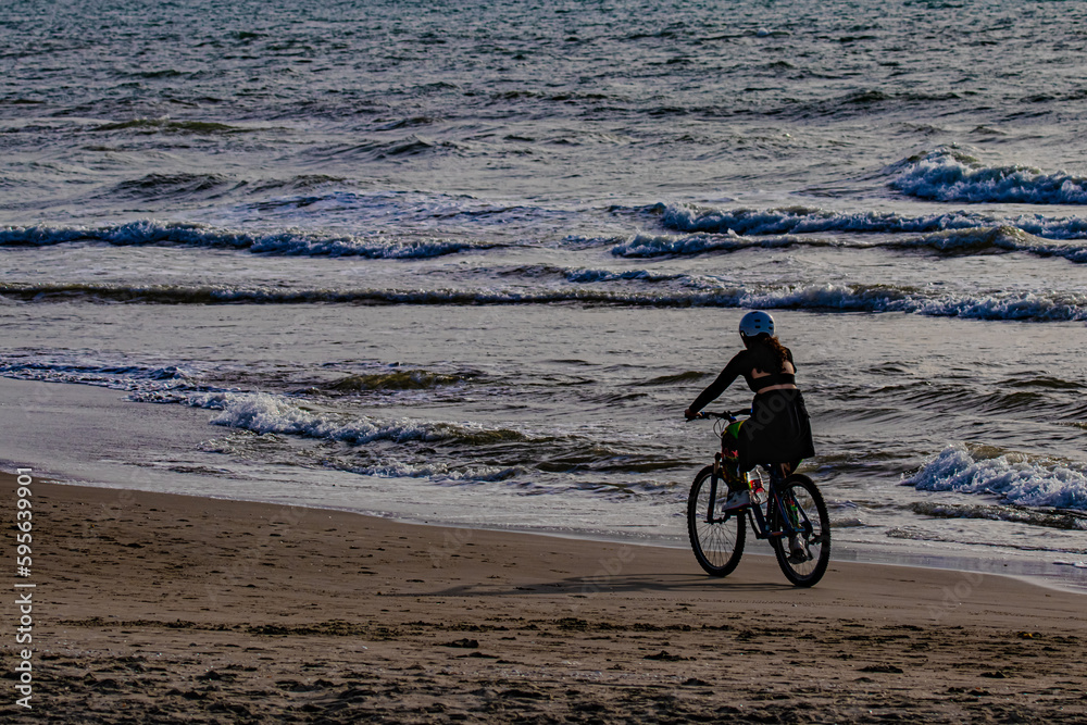 Fototapeta premium Girl riding a bicycle on the beach