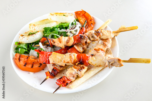A skewered chicken kebob with grilled onions, bell peppers and delicious white meat with seasoning isolated on a white background. Tavuk sis izgara.