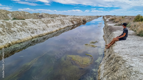 Foto Man sitting at the canals of Bonneville Salt Flats in Wendover, Western Utah, USA, America