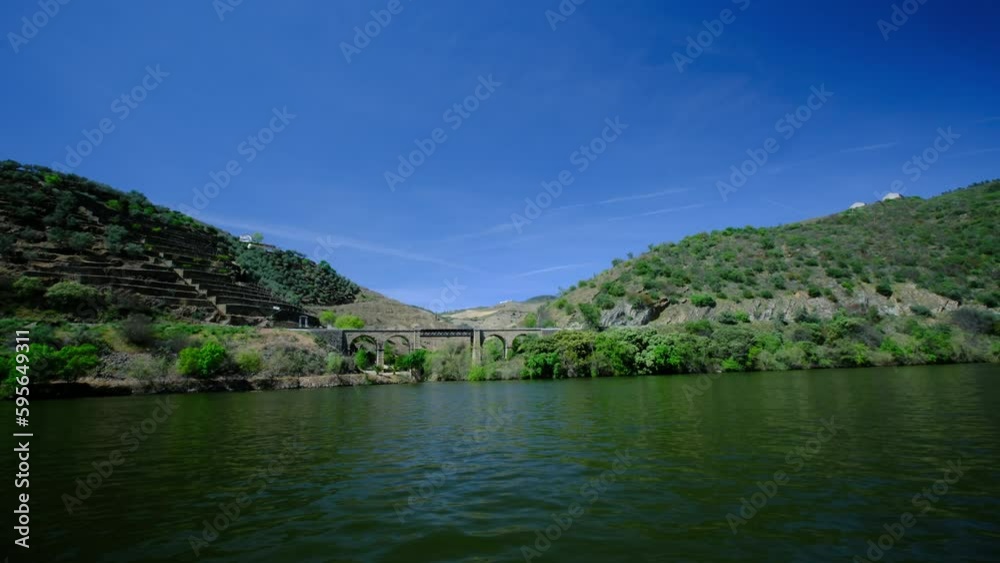 A sunny river cruise, with beautiful blue skies. the river is calm and peaceful, and by the river bank, an old bridge is visible. a 4K video clip, Douro river, Portugal. A sunny river cruise, with beautiful blue skies. the river is calm and peaceful, and by the river bank, an old bridge is visible. a 4K video clip, Douro river, Portugal.