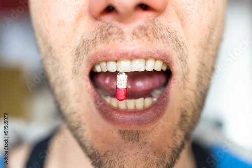 Drugs and Mouth. Closeup of a man taking medicine pill. Mouth view  illness. Medicine concept of viagra  medication for stomach  erection  sleeping  digestive or drugs