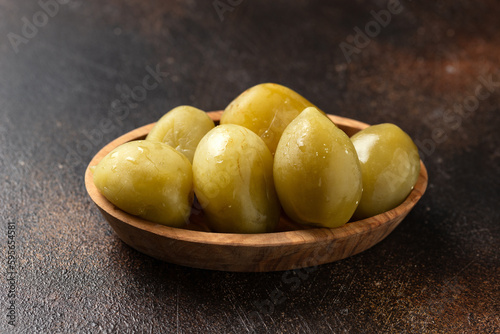 Homemade fermented green tomatoes served in wooden bowl