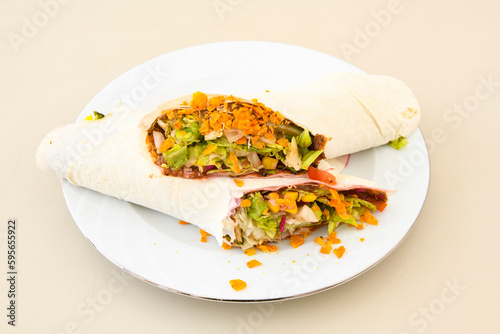 Cig kofte (raw meatball) with lettuce, tomato, pickle and lemon, hot Chee kofta. Turkish local raw food concept.Table scene of assorted take out or delivery foods. Doritoslu cig kofte durum.