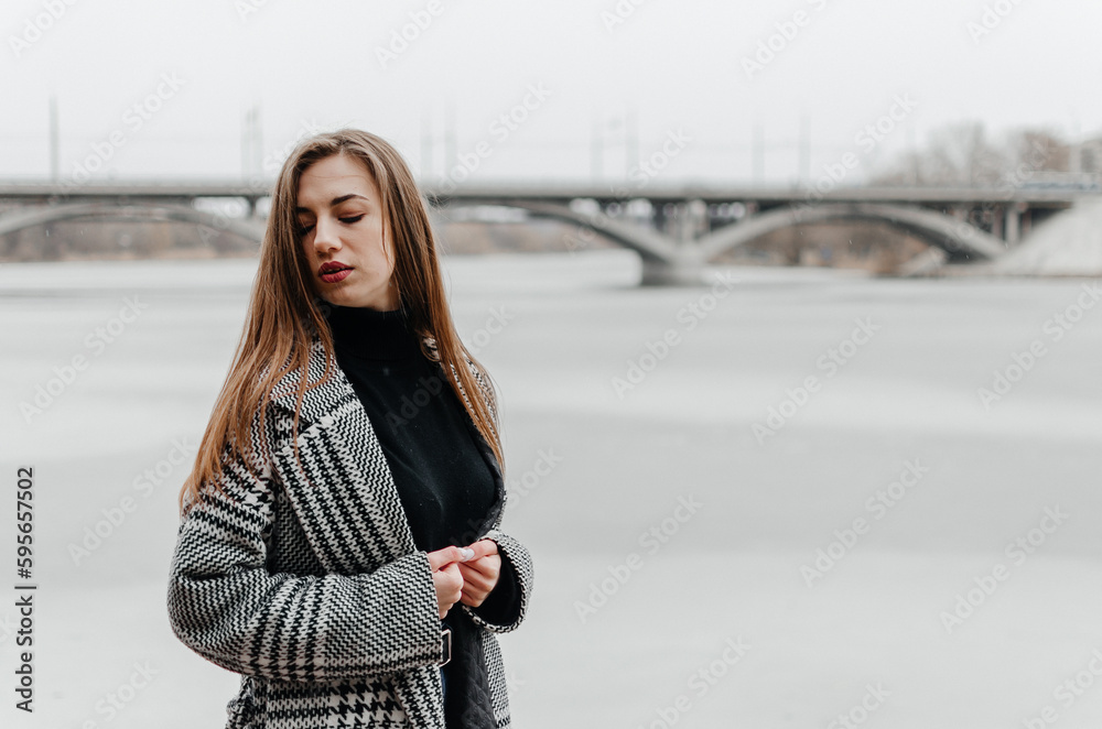 A woman stands by a frozen river