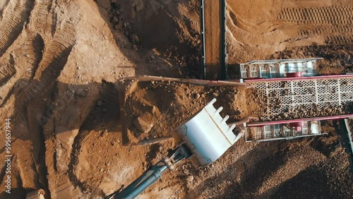 Crushing screening plant. Mining truck loading stones on sorting conveyor belt. Heavy machinery working for minerals extraction. Mining extractive industry.