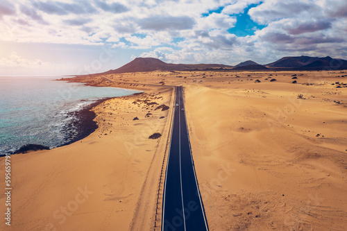 Fuerteventura, Corralejo sand dunes nature park. Beautiful Aerial Shot. Canary Islands, Spain. Aerial view of an empty road through the dunes at the sunset. Fuerteventura, Canary Islands, Spain.