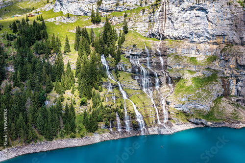 Famous Oeschinensee with Bluemlisalp mountain on a sunny summer day. Panorama of the azure lake Oeschinensee. Swiss alps, Kandersteg. Amazing tourquise Oeschinnensee with waterfalls, Switzerland. photo