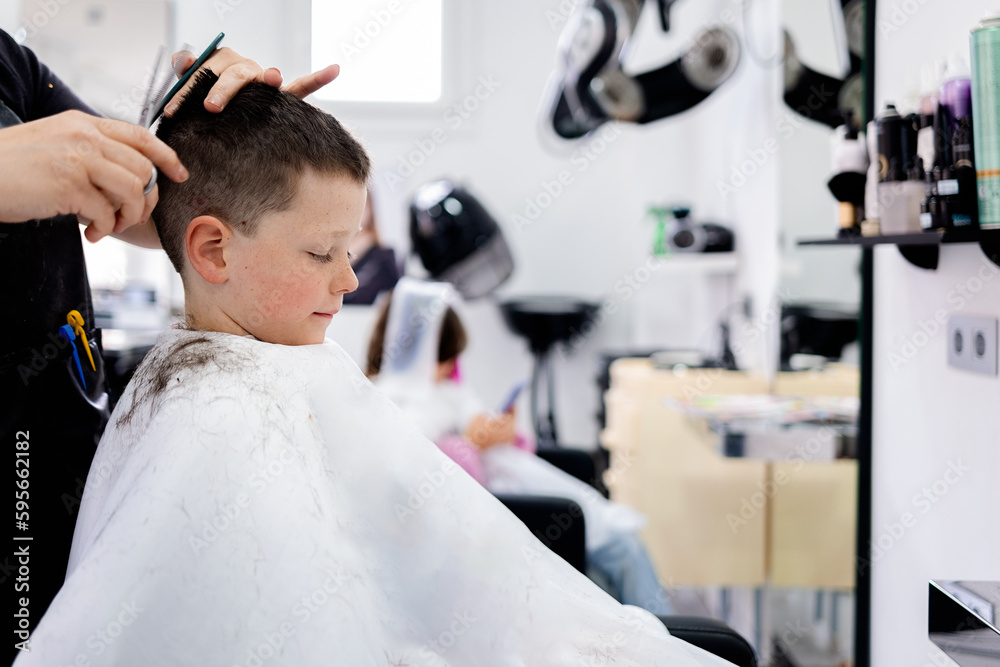 Unrecognizable barber cutting hair of boy in salon Unrecognizable barber cutting hair of boy in salon