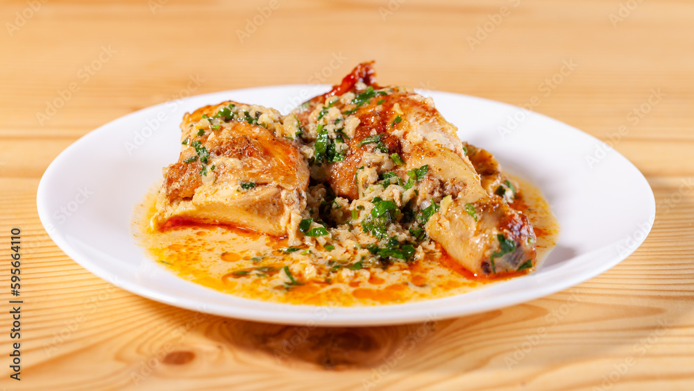 Shkmeruli is a traditional Georgian dish of chicken in garlic sauce in the white plate Shkmeruli is a traditional Georgian dish of chicken in garlic sauce in the white plate