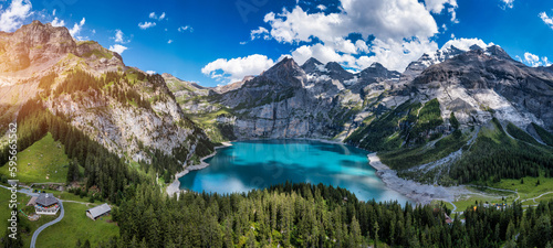 Famous Oeschinensee with Bluemlisalp mountain on a sunny summer day. Panorama of the azure lake Oeschinensee. Swiss alps, Kandersteg. Amazing tourquise Oeschinnensee with waterfalls, Switzerland.