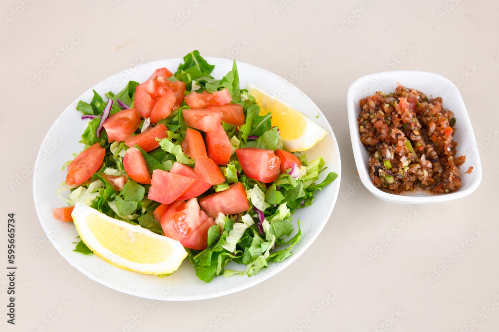 Green salad with arugula, lamb and tomatoes. Healthy vegan dish. Top view at table. Turkish Coban (choban) salata or Shepherds salad, Akdeniz salad in white bowl. Green salad with arugula, lamb and tomatoes. Healthy vegan dish. Top view at table. Turkish Coban (choban) salata or Shepherds salad, Akdeniz salad in white bowl.