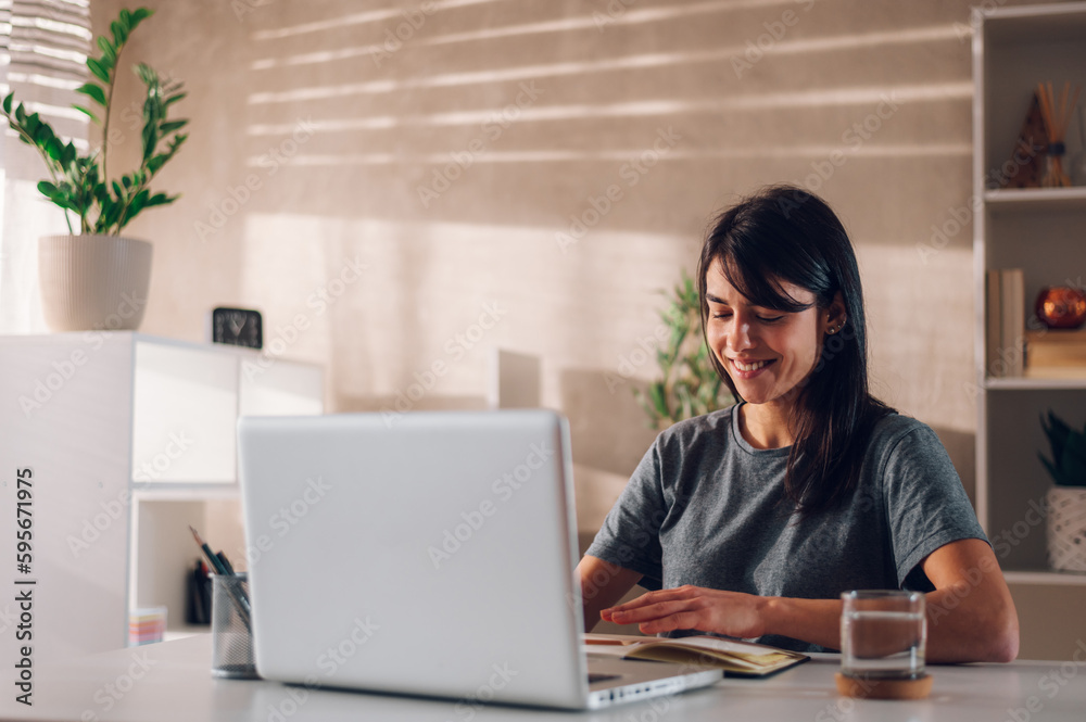 Satisfied young boss lady smiling and sitting at her desk while typing new ideas Satisfied young boss lady smiling and sitting at her desk while typing new ideas